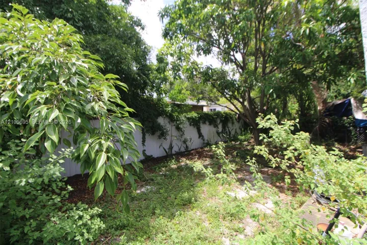 Backyard featuring a white vinyl privacy fence and mature trees