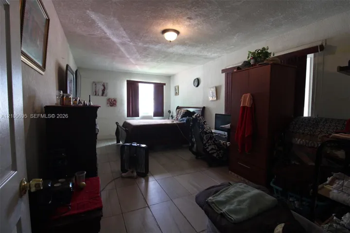 Spacious interior featuring neutral tile flooring, textured ceiling, and natural light from a windowed wall