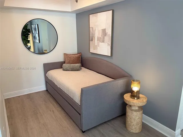 Wood-finish flooring, neutral two-tone wall paint, and a circular wall-mounted mirror