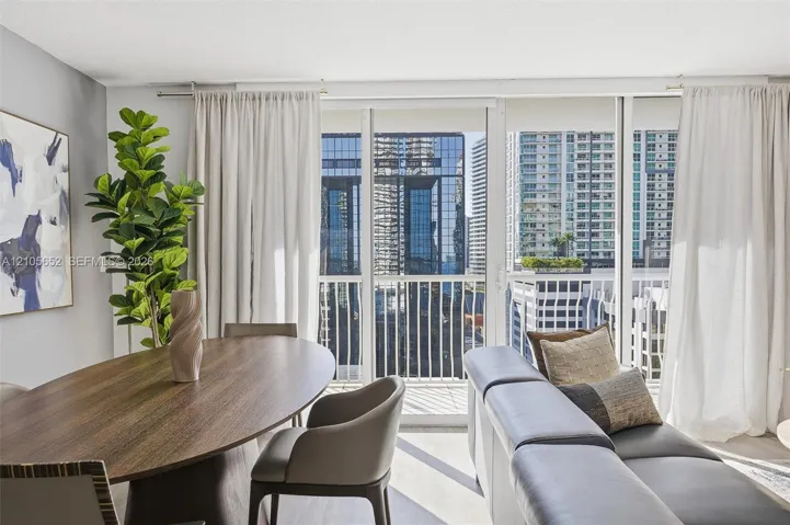 Floor-to-ceiling glass sliding doors, private balcony with metal railing, and neutral wall tones