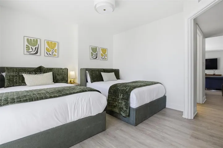 Light-toned wood-finish flooring, crisp white walls, and neutral trim detailing, complemented by a central drum-style ceiling light fixture