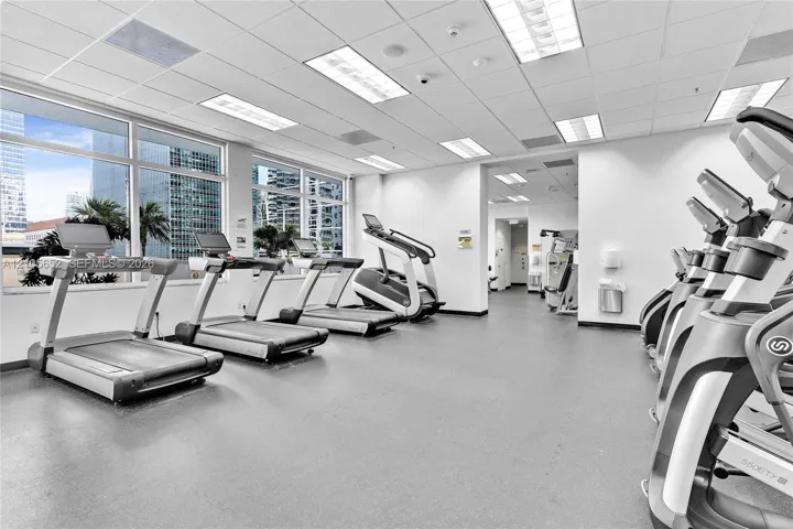 Fitness center featuring expansive floor-to-ceiling windows, recessed drop-ceiling lighting, and rubberized flooring