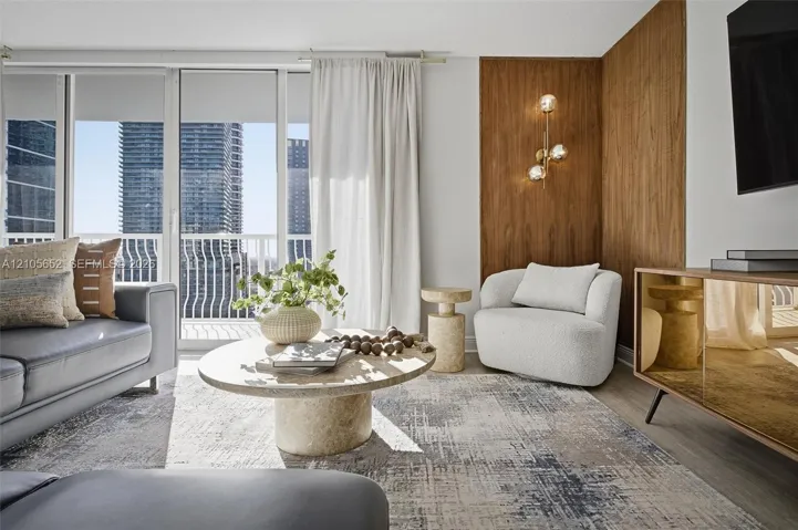 Living area featuring floor-to-ceiling windows, wood-finish wall paneling, and an integrated multi-globe wall sconce