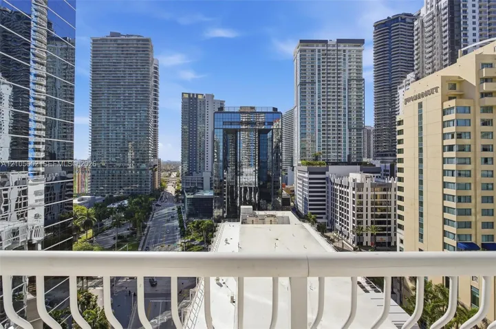 Open-air balcony featuring a white metal railing and a prominent urban skyline backdrop