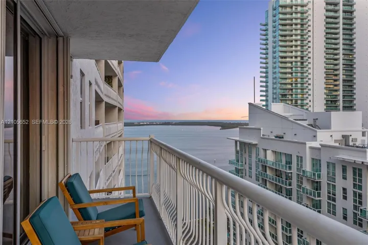 Covered balcony featuring white metal railings and expansive water and urban skyline scenery