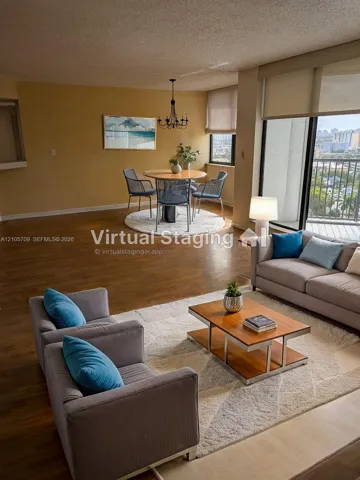 Open living area featuring wood-finish flooring, floor-to-ceiling glass sliding doors, a private balcony, and an overhead chandelier fixture