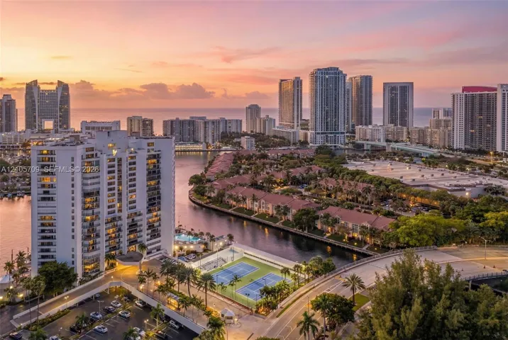 High-rise residential property featuring balcony access, waterfront placement, and proximity to hard-surface tennis courts and lush tropical landscaping