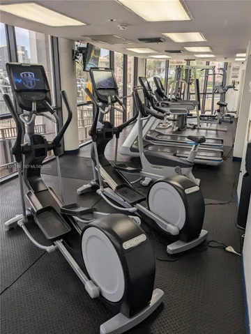 Fitness center featuring rubberized flooring, floor-to-ceiling windows, and recessed ceiling lighting