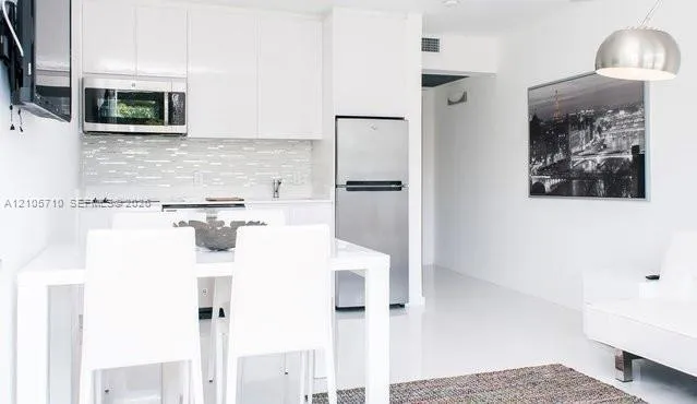 Modern kitchen featuring white flat-panel cabinetry, stainless steel appliances, a horizontal tile backsplash, and polished high-gloss flooring