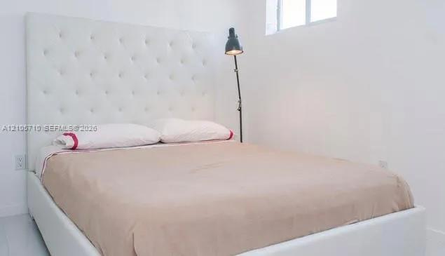 High-profile white tufted headboard, crisp white walls, and bright white flooring