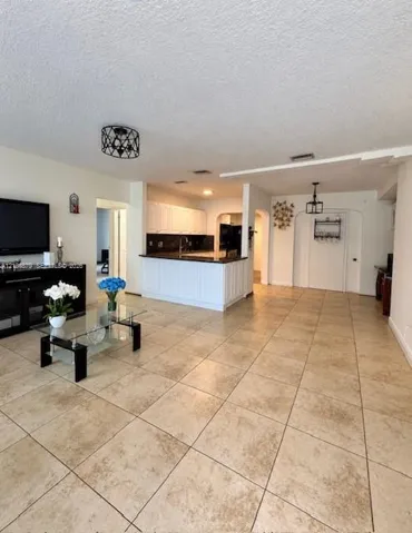 Tiled flooring throughout, white cabinetry, dark countertops, recessed lighting, and a decorative ceiling fixture