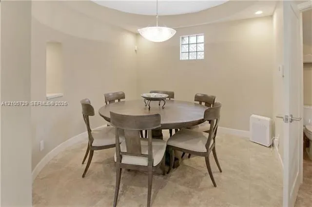 Circular room featuring stone-finish flooring, a recessed wall niche, a square glass-block window, and a central pendant light fixture