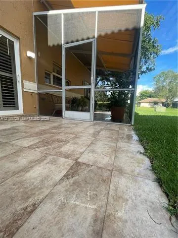 Screened-in patio featuring large-format tile flooring and a retractable canvas awning