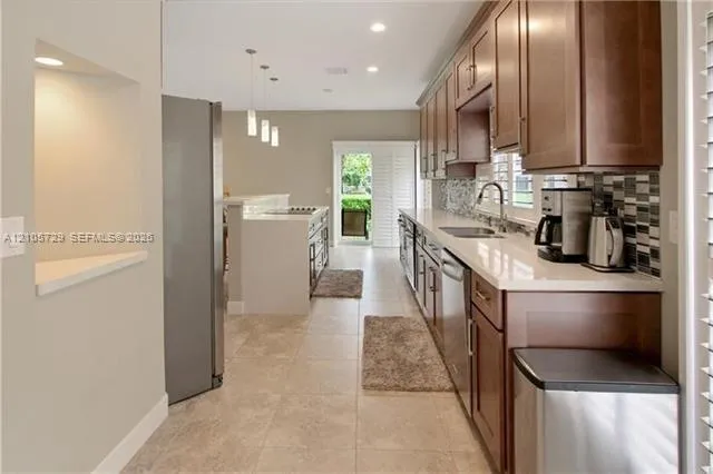 Kitchen featuring wood cabinetry, stone-finish countertops, tile backsplash, tile flooring, and recessed lighting