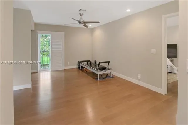 Open legal 4th bedroom, used as family space. Can easily be closed. Room featuring wood-finish flooring, neutral wall paint, recessed lighting, a brushed-metal ceiling fan, and glass-paneled sliding door with louvered shutters