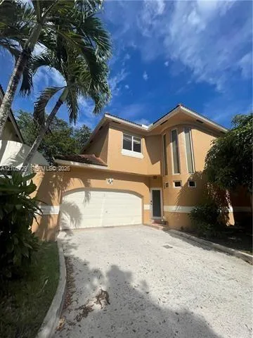 Two-story exterior featuring a stucco facade, arched garage door, multi-level roofline, vertical accent windows, and a paved driveway