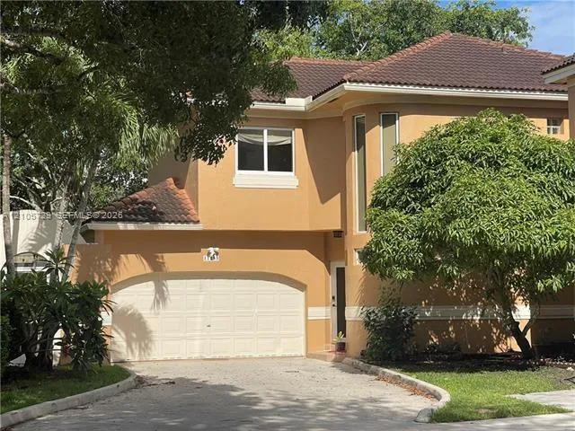 Two-story exterior featuring a stucco facade, tiled roof, arched double-car garage, and vertical accent windows