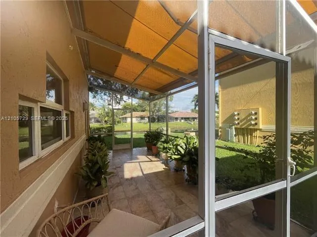 Screened-in lanai featuring tile flooring, metal frame construction, and a covered ceiling