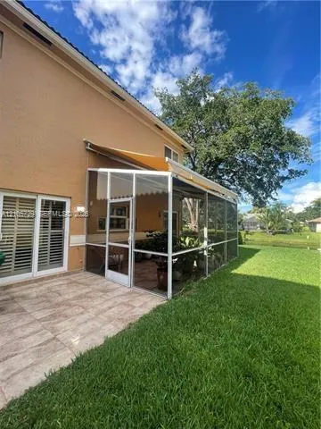 Screened-in lanai featuring a retractable awning, tiled patio flooring, and a sliding glass door entryway