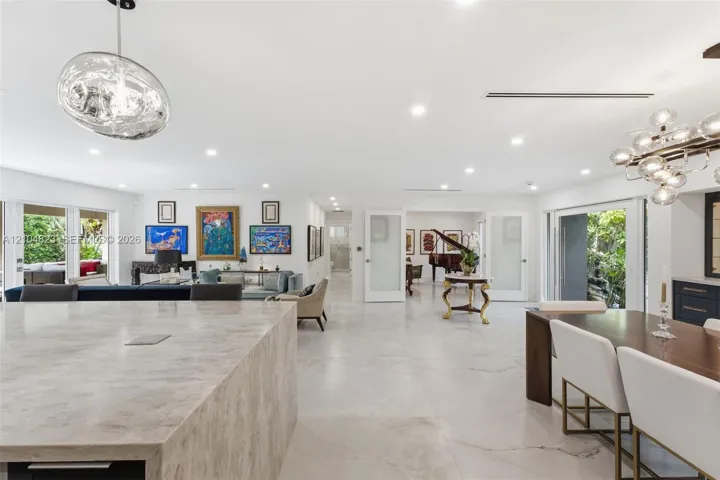 Recessed lighting throughout, wide plank tile flooring, expansive sliding glass doors, built-in cabinetry, and a contemporary chandelier