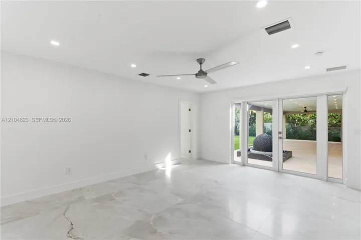 Large-format tiled flooring, recessed ceiling lighting, three-blade ceiling fan, and multi-panel glass door system