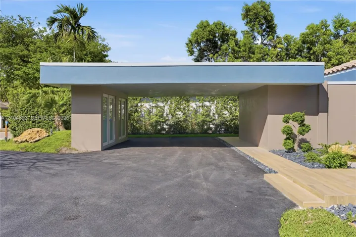 Covered entryway with asphalt driveway and modern landscaping