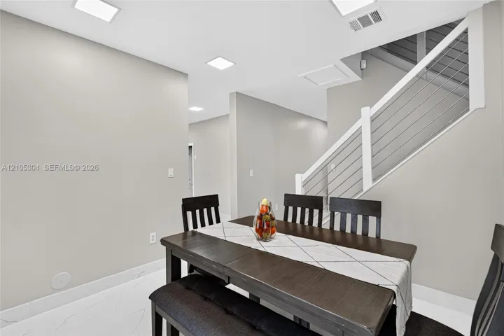 Interior space featuring large-format tile flooring, recessed ceiling lighting, and a staircase with a white handrail and horizontal metal cable railing