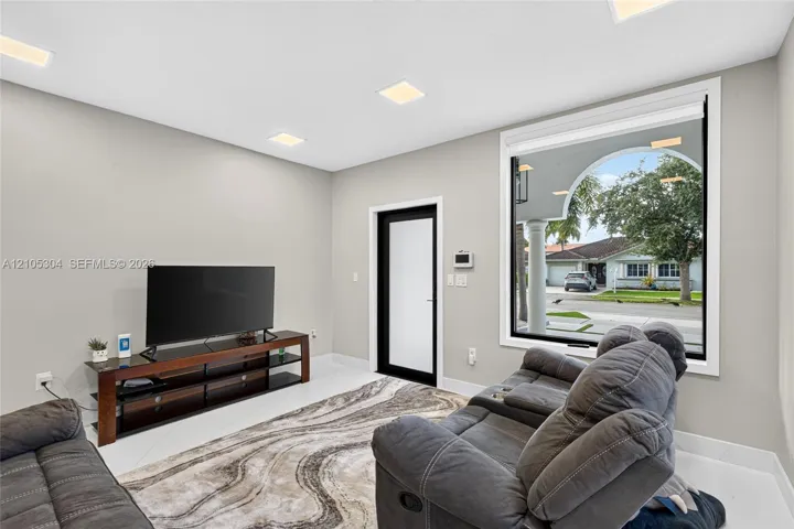 Interior space featuring recessed lighting, smooth-finish walls, large-format tile flooring, a glass-panel door with a black frame, and a wide-format window