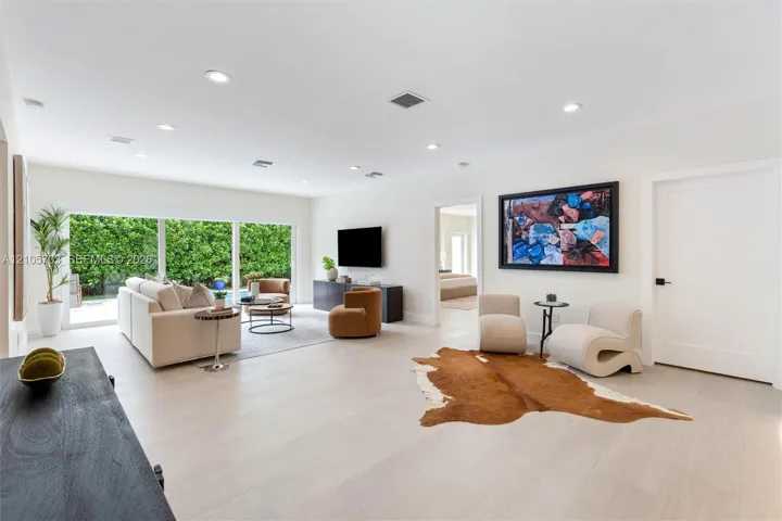 Open floor plan featuring light-toned wood-finish flooring, recessed lighting, and large sliding glass doors providing outdoor access