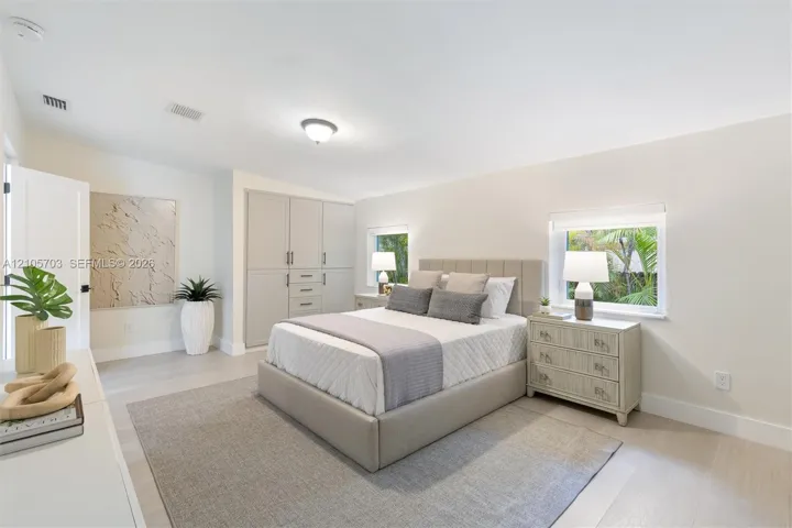 Neutral-toned room featuring light wood-finish flooring, built-in floor-to-ceiling cabinetry, and dual windows