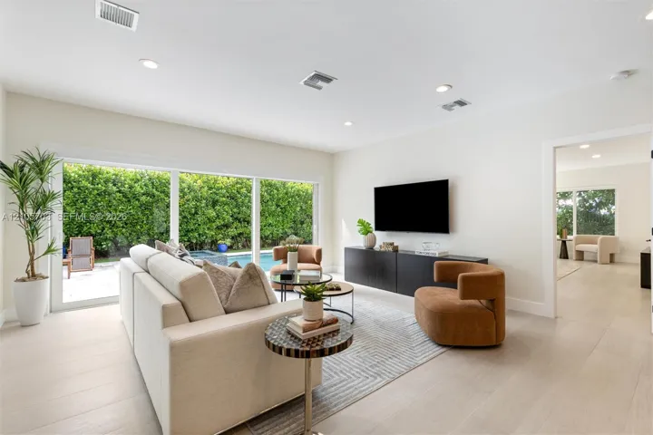 Large sliding glass doors, neutral wood-finish flooring, recessed lighting, and a built-in media console