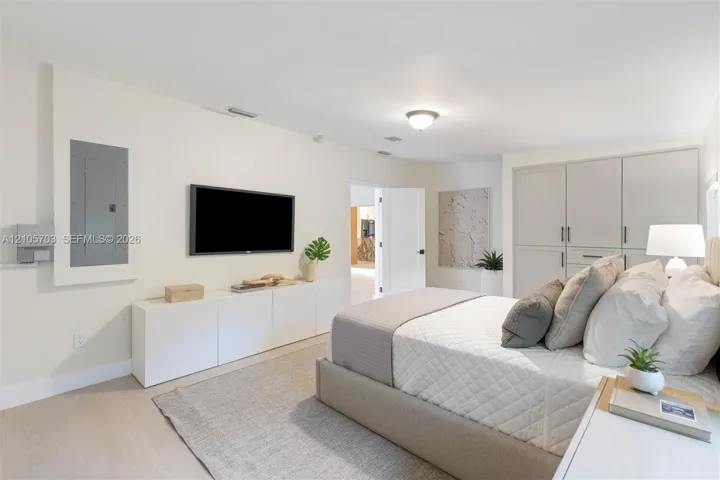 Custom built-in white cabinetry, light-toned wood-finish flooring, integrated wall-mounted electrical panel, and recessed ceiling lighting