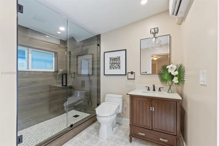 Walk-in shower with wood-finish tile surround, frameless glass enclosure, and rainfall showerhead