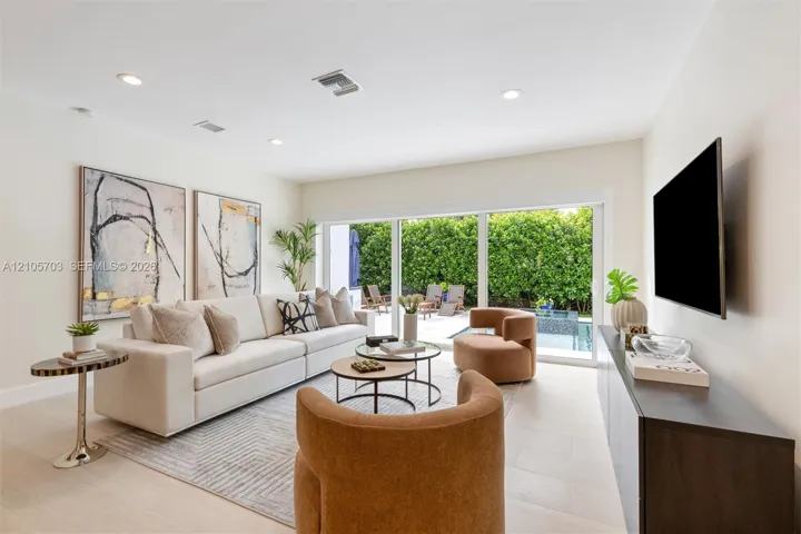 Living space featuring large-format tile flooring, recessed lighting, and full-wall sliding glass doors opening to an exterior patio