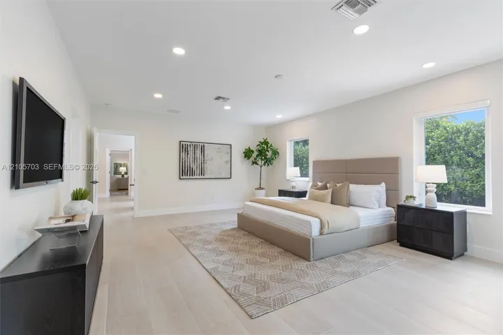 Spacious room featuring neutral interior walls, light-toned wood-finish flooring, recessed ceiling lighting, and multiple windows