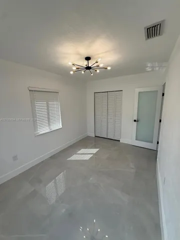 Large-format tile flooring, modern multi-arm sputnik chandelier, frosted glass panel door with matte black hardware, and bi-fold louvered closet doors