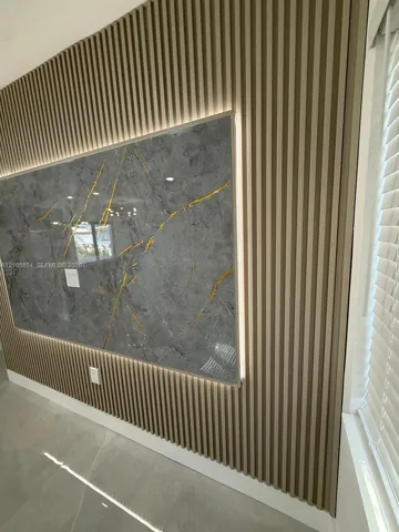 Feature wall with vertical wood-slat paneling, integrated recessed accent lighting, and a large-format grey stone-patterned slab