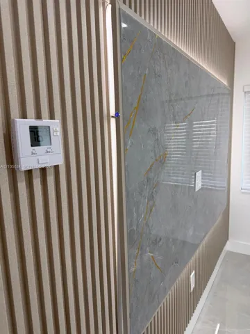Vertical wood-slat wall paneling featuring a large, polished grey-and-gold veined stone-finish accent inlay with integrated perimeter lighting