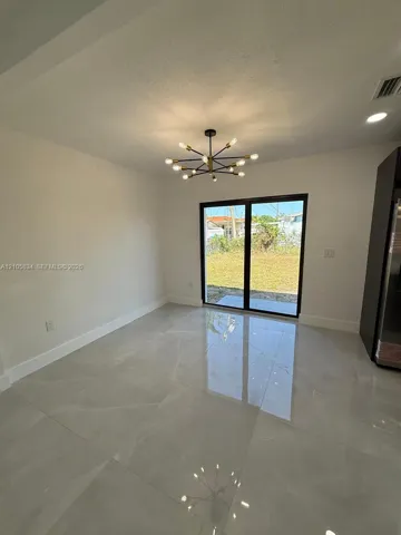 Large-format tile flooring, multi-light contemporary chandelier, and sliding glass doors with black framing