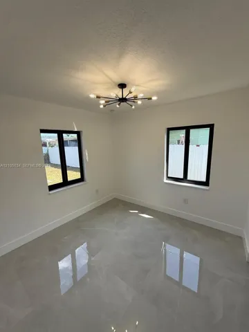 Interior room featuring large-format tile flooring, matte black window frames, and a multi-arm sputnik-style ceiling light fixture