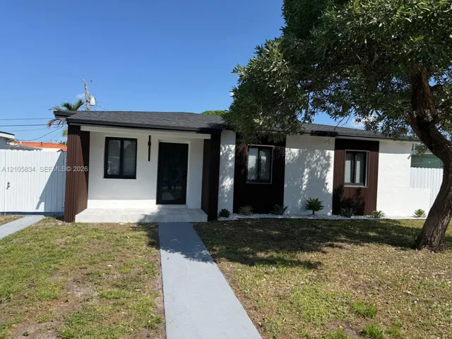 Exterior facade featuring a high-contrast white and dark brown finish, a paved walkway, and white privacy fencing