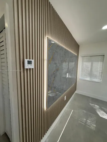 Vertical wood-slat wall paneling featuring an integrated stone-finish accent panel, recessed backlighting, and polished concrete-style flooring