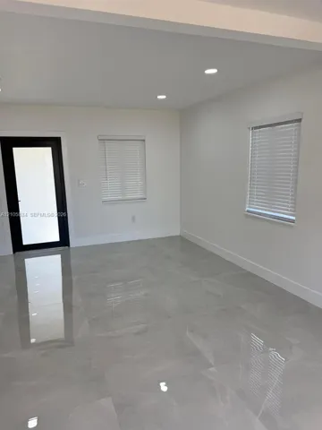Interior space featuring polished stone-finish flooring, recessed lighting, white walls, and a black-framed glass panel door
