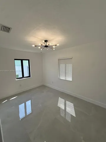 Neutral-toned large-format tile flooring, multi-arm matte black sputnik chandelier, and black-framed windows with horizontal blinds