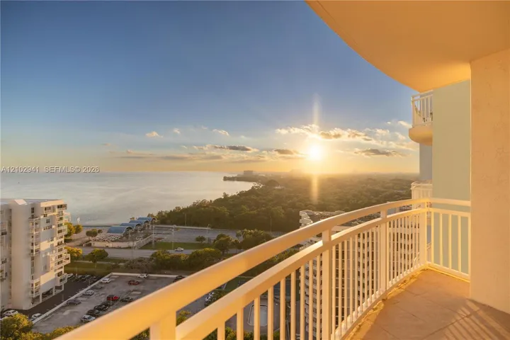 Covered outdoor balcony featuring white railings, tiled flooring, and sweeping panoramic ocean and coastal scenery