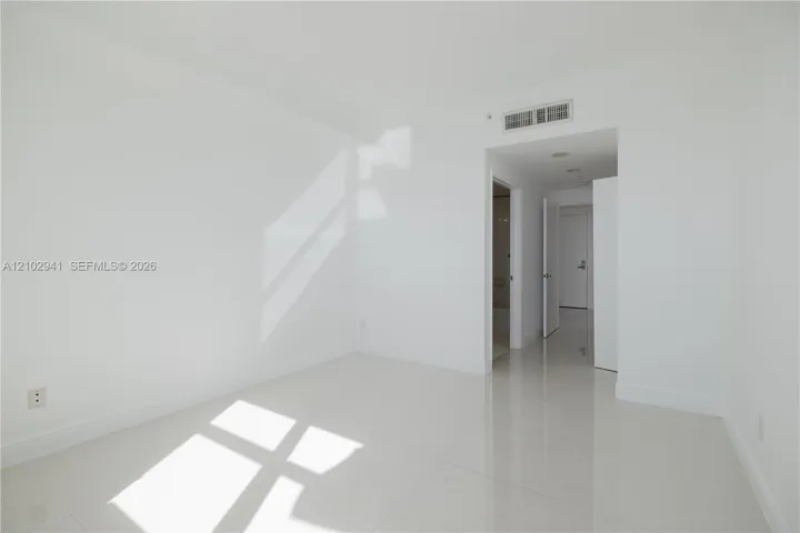 Neutral-toned interior space featuring polished tile flooring, recessed ceiling lighting, and smooth-finish walls