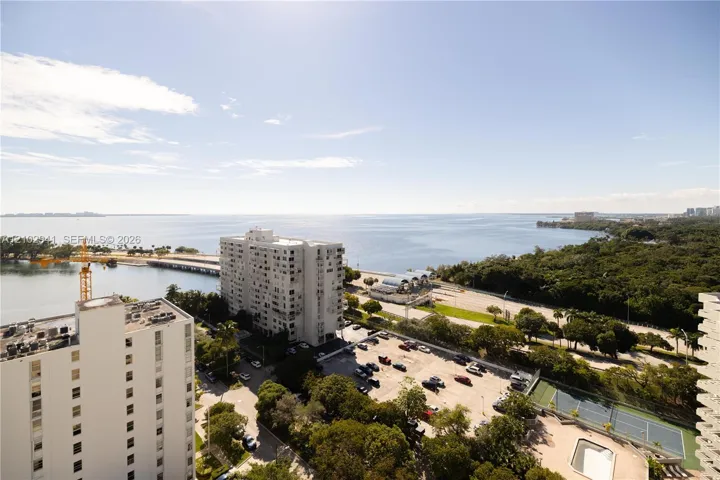 Elevated water frontage featuring expansive coastal scenery, mature tree canopy, integrated hardcourt, and paved surface lot