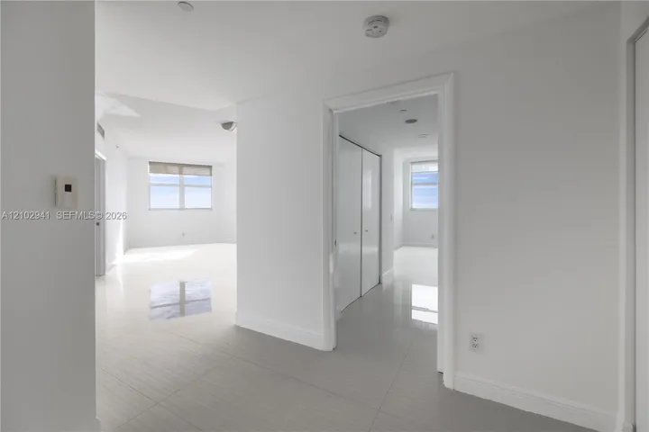 Interior space featuring polished tile flooring, white walls, and floor-to-ceiling closets with sliding panel doors