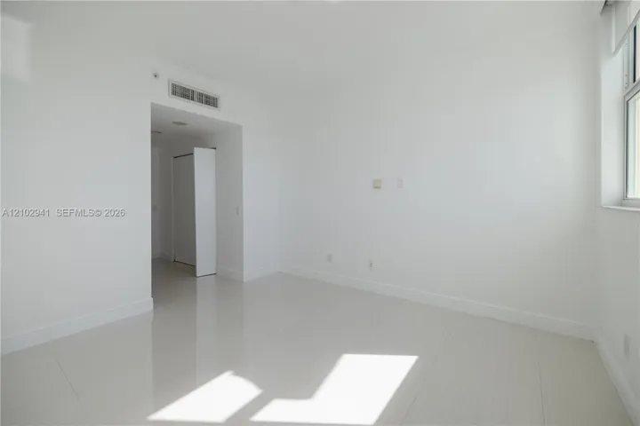 Interior space featuring polished tile flooring, neutral wall finishes, and a window with white casing
