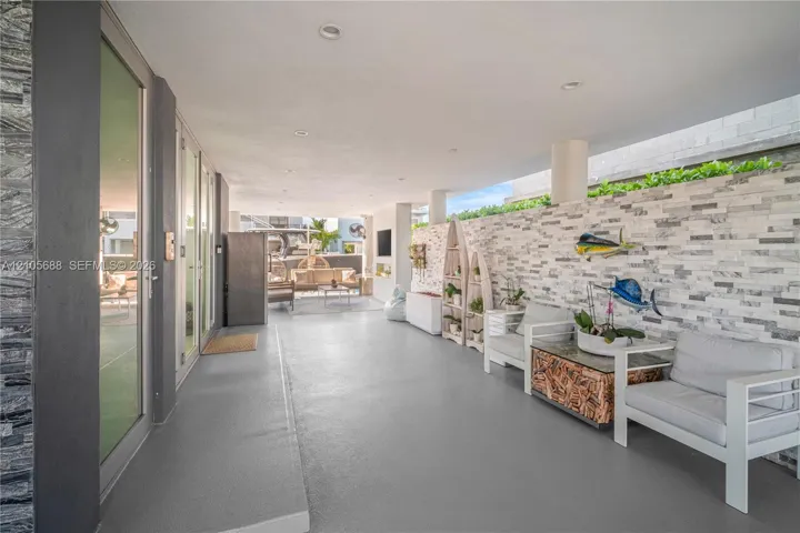 Covered patio featuring a stacked stone accent wall, recessed lighting, concrete flooring, and full-height glass door panels